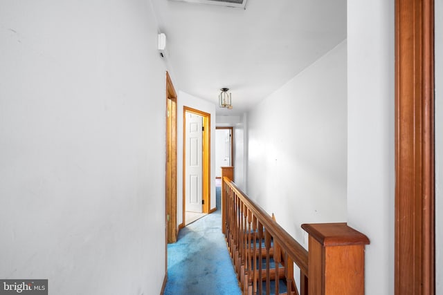 hallway with light colored carpet and an upstairs landing