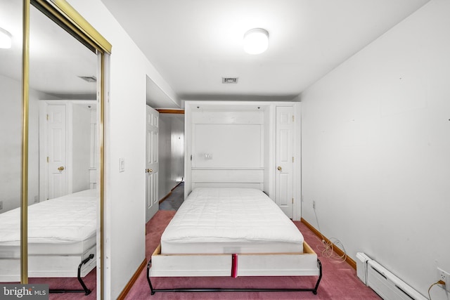 carpeted bedroom featuring visible vents, a baseboard heating unit, and baseboards