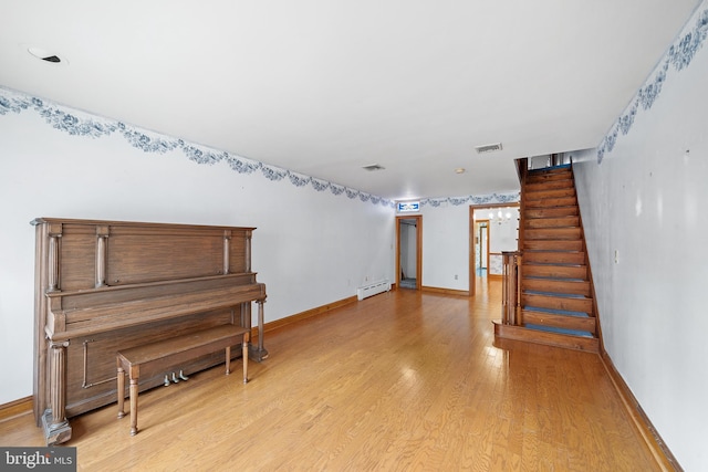 interior space with visible vents, baseboards, a baseboard radiator, light wood-style flooring, and stairway