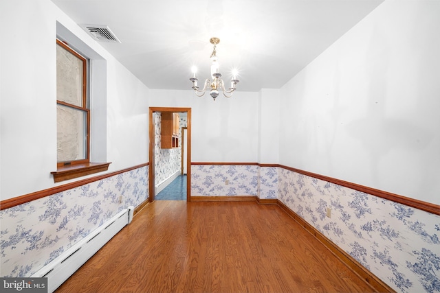 spare room with wallpapered walls, a baseboard radiator, visible vents, and an inviting chandelier