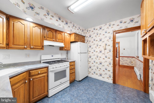 kitchen featuring white appliances, under cabinet range hood, light countertops, and wallpapered walls