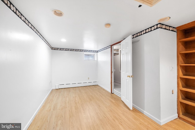 empty room featuring baseboards, baseboard heating, and light wood-style floors