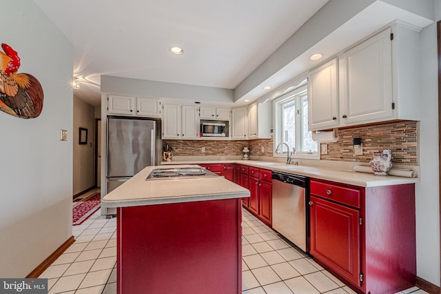 kitchen with light tile patterned floors, white cabinets, appliances with stainless steel finishes, a center island, and light countertops