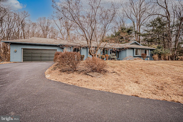 ranch-style house with an attached garage and aphalt driveway