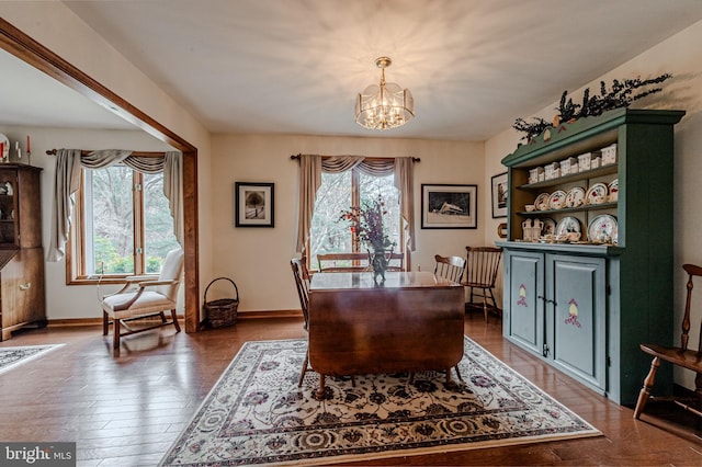 dining space featuring baseboards, a notable chandelier, and wood finished floors