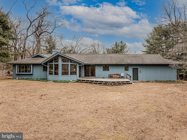 back of property featuring a yard, a chimney, and a wooden deck