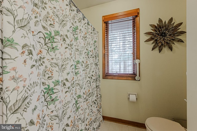 bathroom with toilet, curtained shower, baseboards, and tile patterned floors