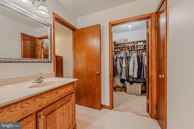 bathroom with a walk in closet and vanity