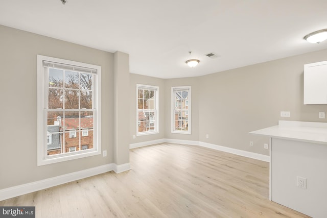 unfurnished dining area featuring light wood-style flooring, baseboards, and visible vents