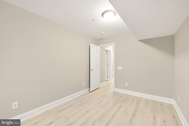 spare room with baseboards and light wood-type flooring