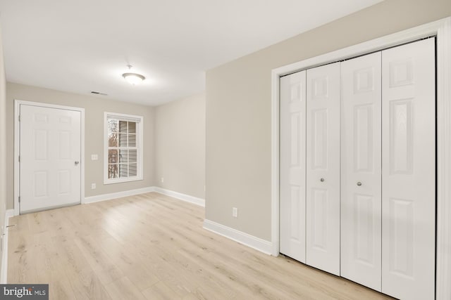 unfurnished bedroom featuring a closet, visible vents, light wood-type flooring, and baseboards