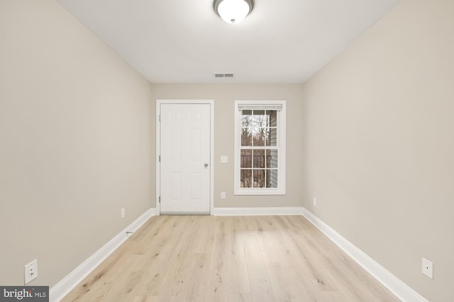 empty room featuring baseboards, visible vents, and light wood finished floors