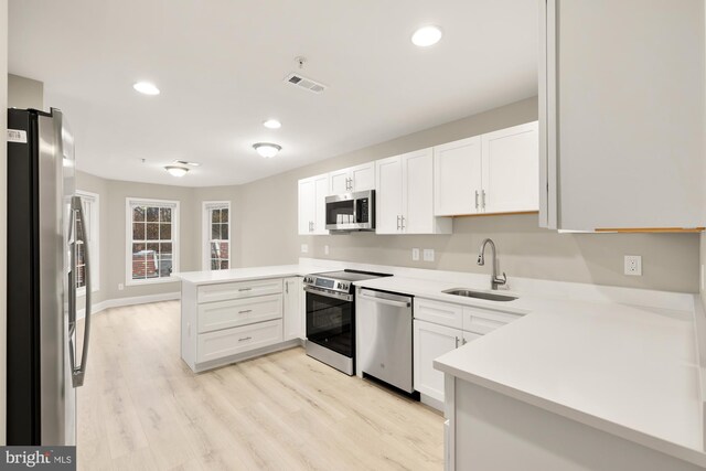 kitchen featuring visible vents, a peninsula, a sink, stainless steel appliances, and light countertops