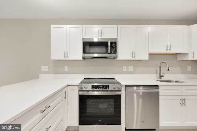 kitchen featuring a sink, appliances with stainless steel finishes, white cabinets, and light countertops