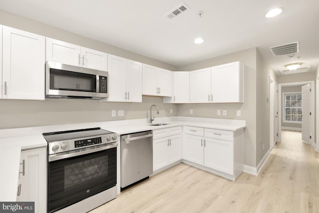 kitchen with visible vents, a sink, stainless steel appliances, white cabinets, and light countertops