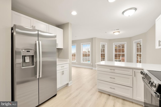 kitchen with light countertops, white cabinets, light wood-style floors, and appliances with stainless steel finishes