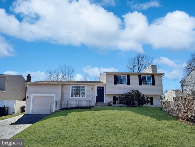 tri-level home featuring driveway, a garage, a chimney, fence, and a front lawn