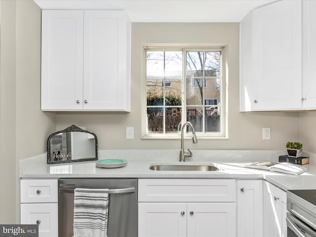 kitchen featuring stainless steel dishwasher, a sink, and white cabinets