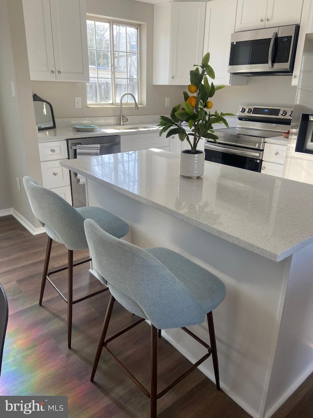 kitchen featuring white cabinetry, stainless steel appliances, and a breakfast bar area