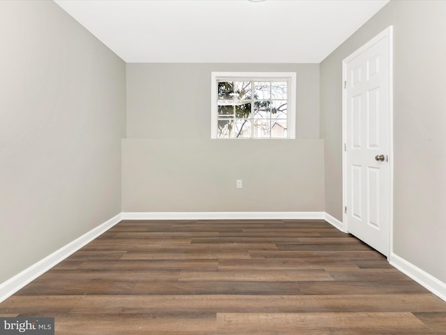 spare room with dark wood-style floors and baseboards