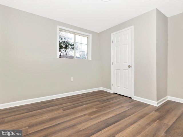 unfurnished room featuring dark wood-type flooring and baseboards