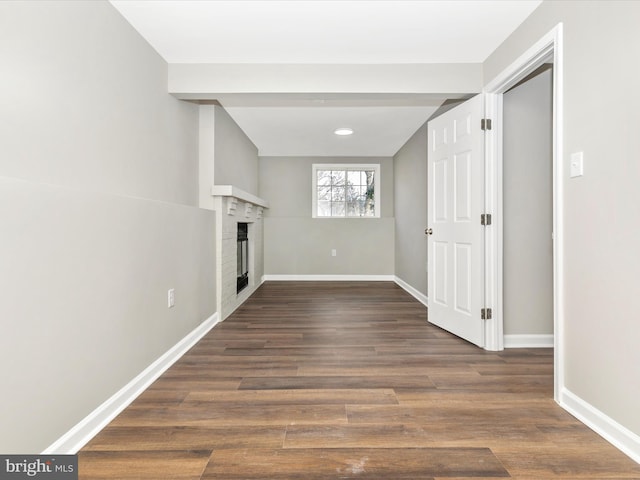 interior space with dark wood-type flooring, a fireplace, and baseboards