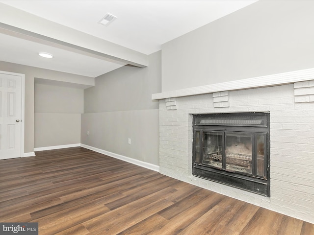 unfurnished living room with visible vents, a fireplace, baseboards, and wood finished floors