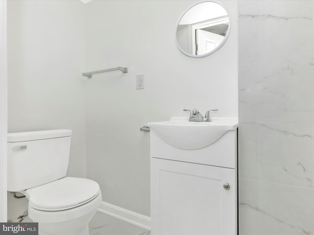 bathroom featuring marble finish floor, toilet, vanity, and baseboards