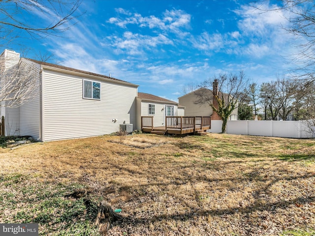 back of property with central AC unit, a lawn, a chimney, fence, and a deck