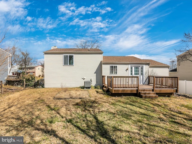 rear view of house featuring a yard, a chimney, fence, a deck, and cooling unit