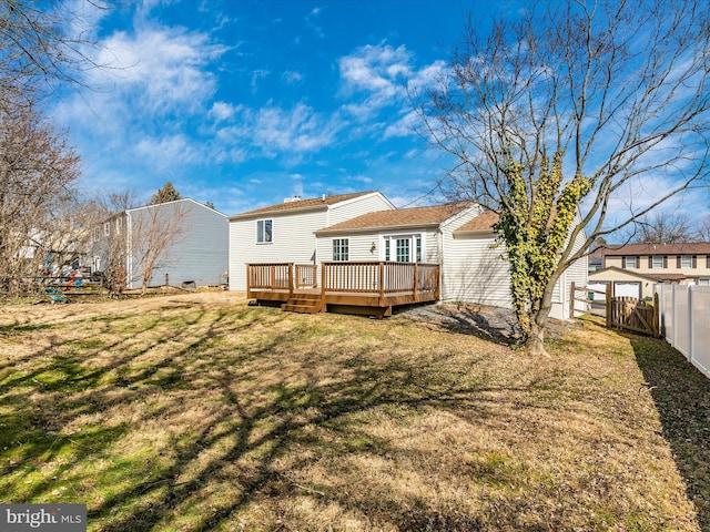 back of property with a wooden deck, fence, and a yard