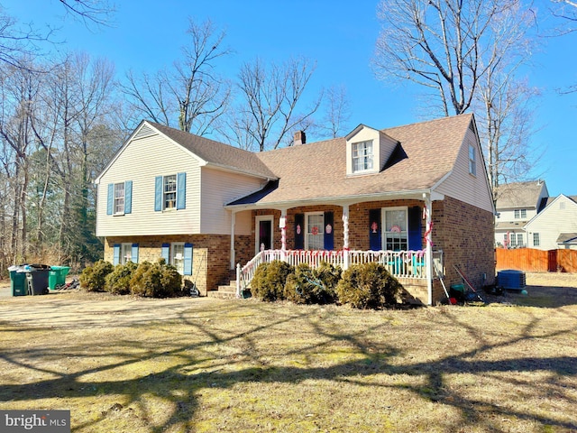 split level home with covered porch, a chimney, a front lawn, and brick siding