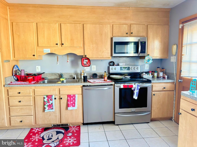 kitchen with light tile patterned floors, light countertops, appliances with stainless steel finishes, light brown cabinets, and a sink