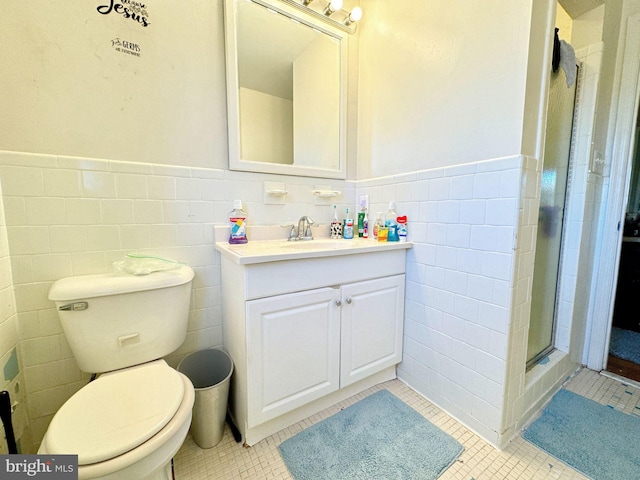 full bath with a stall shower, tile patterned flooring, wainscoting, and vanity