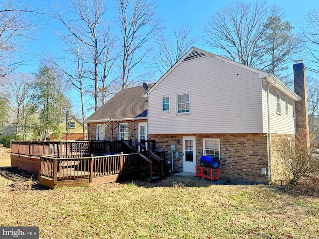 rear view of property with brick siding, a yard, a chimney, and a wooden deck