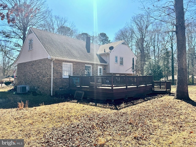 back of property featuring a chimney, roof with shingles, a deck, cooling unit, and brick siding