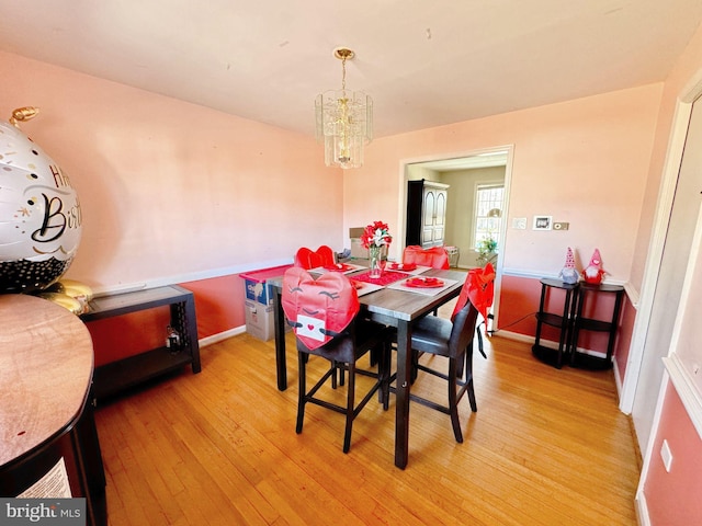 dining space with light wood-style floors, baseboards, and a chandelier