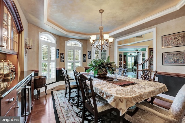 dining area with beverage cooler, a wainscoted wall, ornamental molding, dark wood-type flooring, and an inviting chandelier