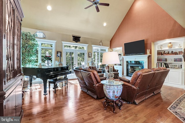 living area featuring french doors, a fireplace, recessed lighting, wood-type flooring, and high vaulted ceiling