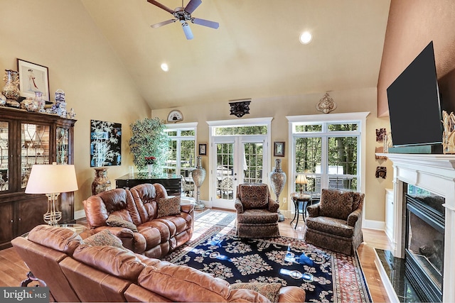 living room with baseboards, a premium fireplace, wood finished floors, french doors, and high vaulted ceiling