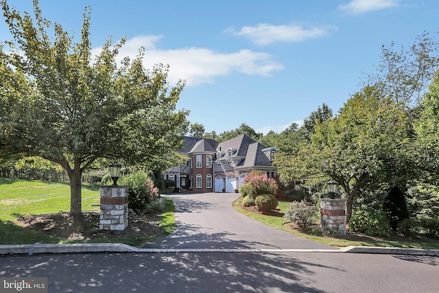 view of front facade with aphalt driveway, an attached garage, and a front yard