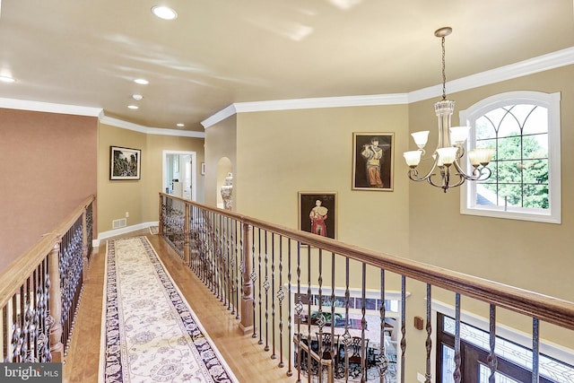 hallway featuring ornamental molding, a notable chandelier, baseboards, and wood finished floors