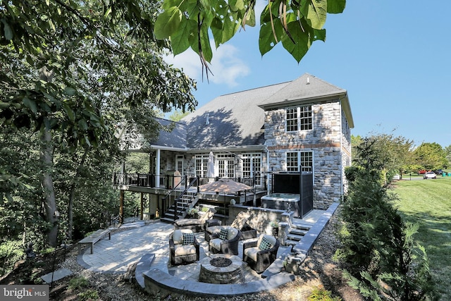 rear view of property with an outdoor fire pit, a patio area, a deck, stone siding, and stairs