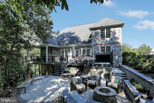 rear view of property with a fire pit, a patio, stone siding, stairway, and a wooden deck