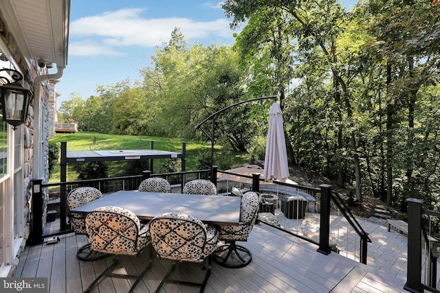 wooden deck with a yard and outdoor dining area