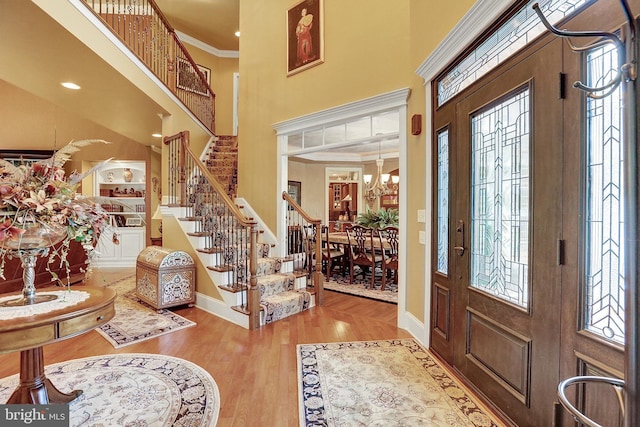 foyer entrance with a high ceiling, ornamental molding, wood finished floors, baseboards, and stairs