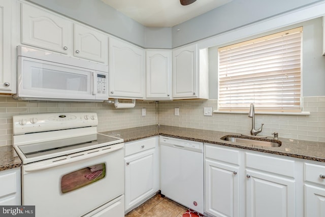 kitchen featuring dark stone counters, white appliances, a sink, and white cabinetry