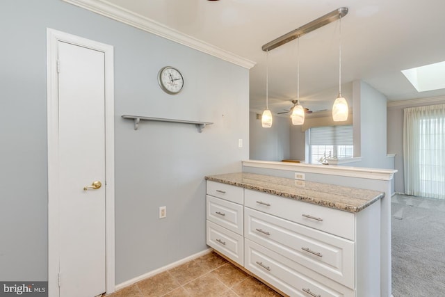 kitchen with a peninsula, a skylight, white cabinets, hanging light fixtures, and crown molding