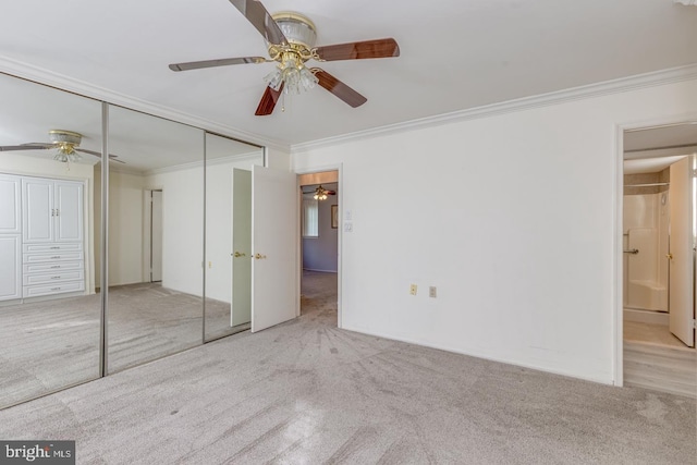 unfurnished bedroom featuring ornamental molding, a closet, light colored carpet, and ceiling fan