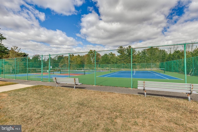 view of tennis court with a yard and fence